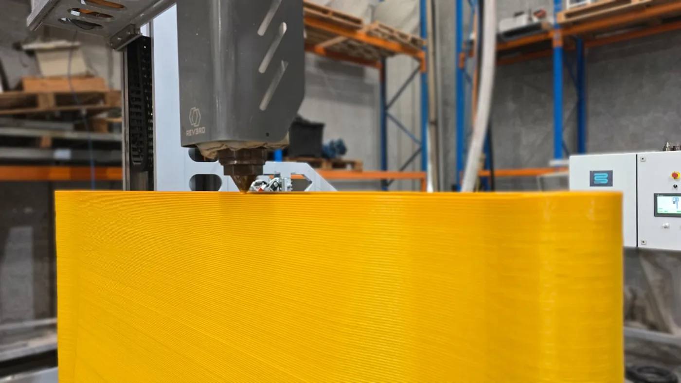 The pellet extruder laying a FeatherCrete panel, the printed layers visible across its face